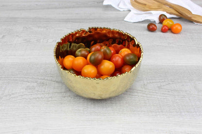Pampa Bay Golden Millennium medium bowl in hammered gold porcelain on a table with cherry tomatoes inside