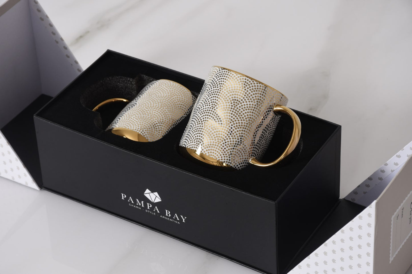 Two decorative mugs with gold accents in a black Pampa Bay box.

Pampa Bay Get Gifty Set of 2 Dotted Gold Porcelain Mugs in Gift Box

Luxury gold dotted porcelain mugs with gold handles

Elegant Pampa Bay mug gift set for coffee and tea